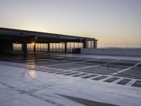 an airport parking area with the sun setting in the sky behind it, overcast