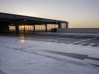 an airport parking area with the sun setting in the sky behind it, overcast