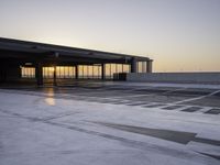 an airport parking area with the sun setting in the sky behind it, overcast