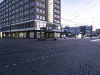 the street corner in front of a tall building has windows and a black car driving past