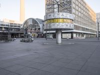 a clock with numbers is sitting on the middle of the street near some tall buildings