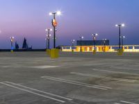 parking lot at dusk with several traffic lights next to it and multiple cars parked in front of the building