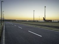 an airplane on the runway of an airport near a light pole and field with lights