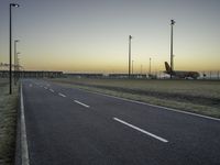 an airplane on the runway of an airport near a light pole and field with lights