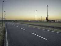 an airplane on the runway of an airport near a light pole and field with lights