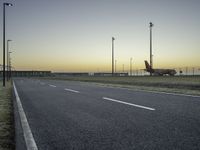 an airplane on the runway of an airport near a light pole and field with lights