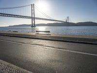 a person is running and riding on the street near the water below the bridge in the evening