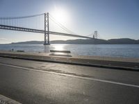 a person is running and riding on the street near the water below the bridge in the evening