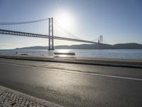 a person is running and riding on the street near the water below the bridge in the evening