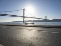 a person is running and riding on the street near the water below the bridge in the evening