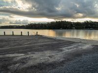 the man sits by the lake alone on a cloudy day and his laptop is turned away from him