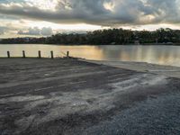 the man sits by the lake alone on a cloudy day and his laptop is turned away from him