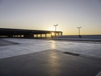 an empty parking lot with no cars in it at sunset with sun going down in distance