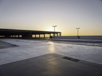 an empty parking lot with no cars in it at sunset with sun going down in distance