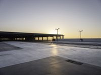 an empty parking lot with no cars in it at sunset with sun going down in distance