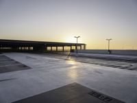 an empty parking lot with no cars in it at sunset with sun going down in distance