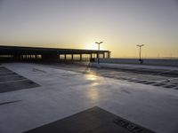 an empty parking lot with no cars in it at sunset with sun going down in distance