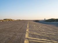 an empty parking lot near the beach and grassy grass at sunset time with the sand dunes up side