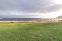 a golf course is next to a lake at dusk on a beach shorefront with clouds over it