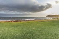 a golf course is next to a lake at dusk on a beach shorefront with clouds over it