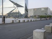 two bicycles parked on a city street in front of some modern buildings that are reflecting their reflective glass