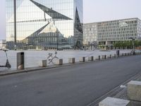 two bicycles parked on a city street in front of some modern buildings that are reflecting their reflective glass