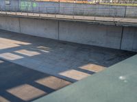 a skateboarder riding on a cement ramp next to a city street under a bridge