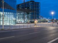 a street with a bunch of parked buses on it's side, and large glass buildings near by