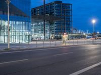 a street with a bunch of parked buses on it's side, and large glass buildings near by