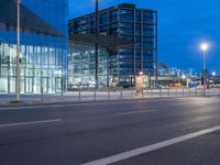 a street with a bunch of parked buses on it's side, and large glass buildings near by