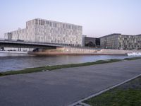 a street bridge over the water next to tall buildings and grassy area with green grass on either side of the road