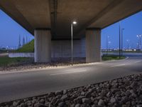 a roadway under a bridge filled with lit up lights and rocks on either side of the road