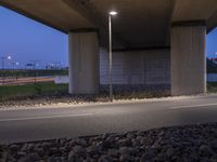 a roadway under a bridge filled with lit up lights and rocks on either side of the road