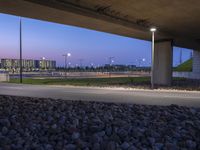 a roadway under a bridge filled with lit up lights and rocks on either side of the road