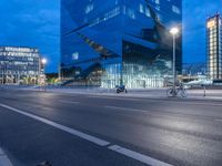 bike and car driving in the evening in front of a modern office building with glass windows