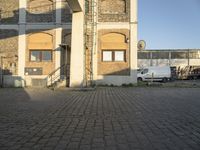 a white van parked in front of an old building with stairs up to the second floor