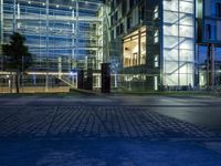 large glass building on the corner at night with people and steps leading to it and stairs