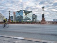 a cyclist and cyclist cross a bridge on a city street with other buildings in the background