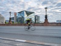 a cyclist and cyclist cross a bridge on a city street with other buildings in the background