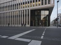 an empty city street with a pedestrian crossing the street in front of the building on the left