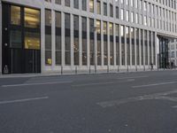 an empty city street with a pedestrian crossing the street in front of the building on the left