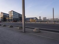 some people are walking down the sidewalk by a road with many large buildings in the background