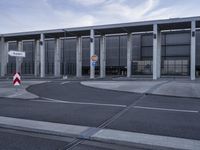 a grey building with many columns and a sign for there is a red stop sign