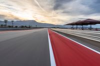 a photo of a dirt race track with sun setting in the distance of the track