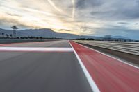 a photo of a dirt race track with sun setting in the distance of the track