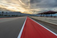 a photo of a dirt race track with sun setting in the distance of the track