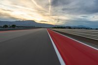 a photo of a dirt race track with sun setting in the distance of the track