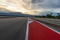 a photo of a dirt race track with sun setting in the distance of the track