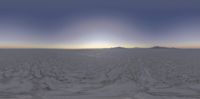 a snow covered desert with the sun setting behind it and an alien like light beam