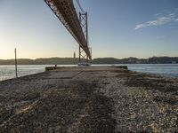 a bridge crosses the ocean from the shore to the dock in the morning sun rises